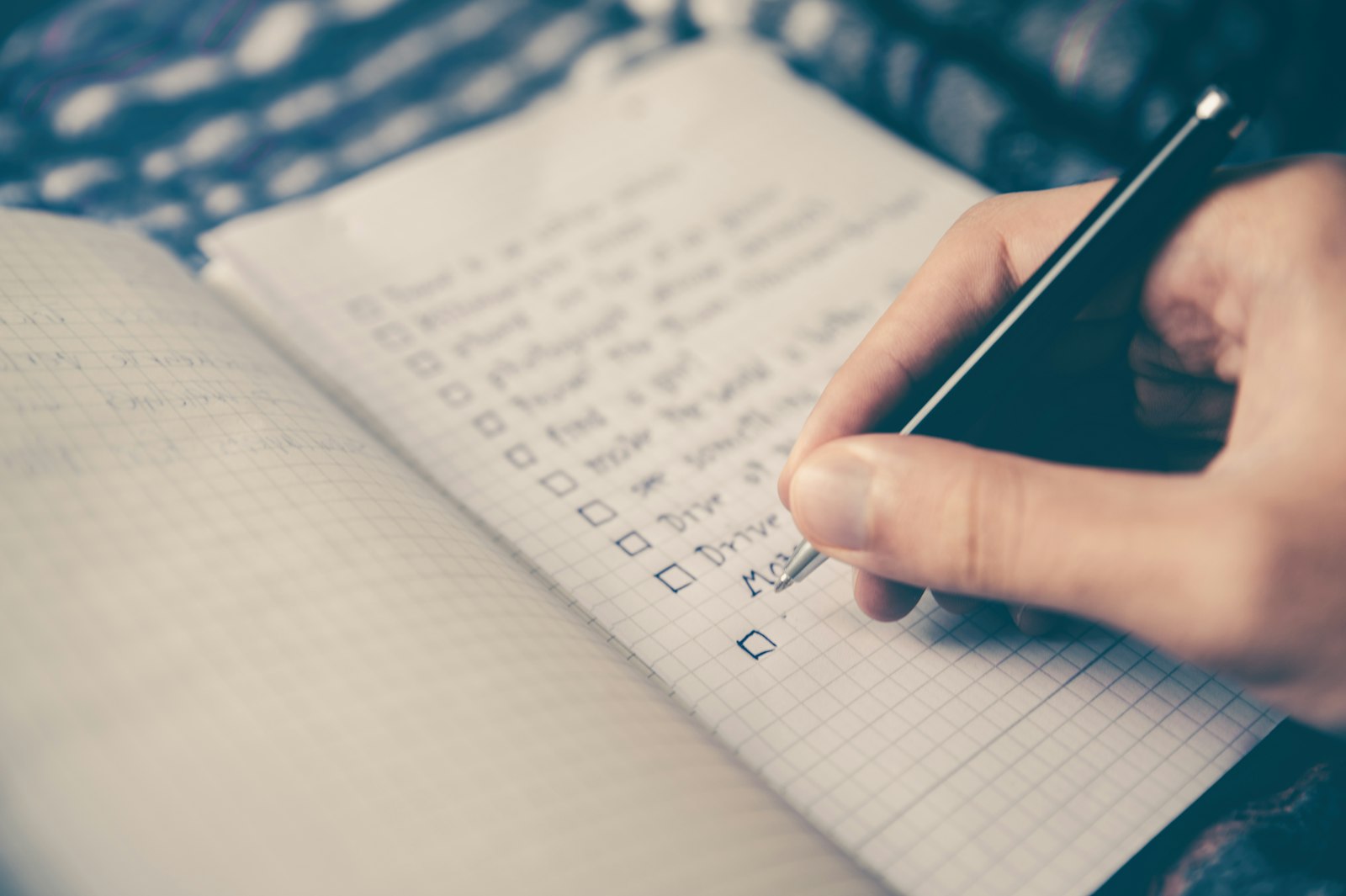 A business owner checking off a to-do list in a notebook